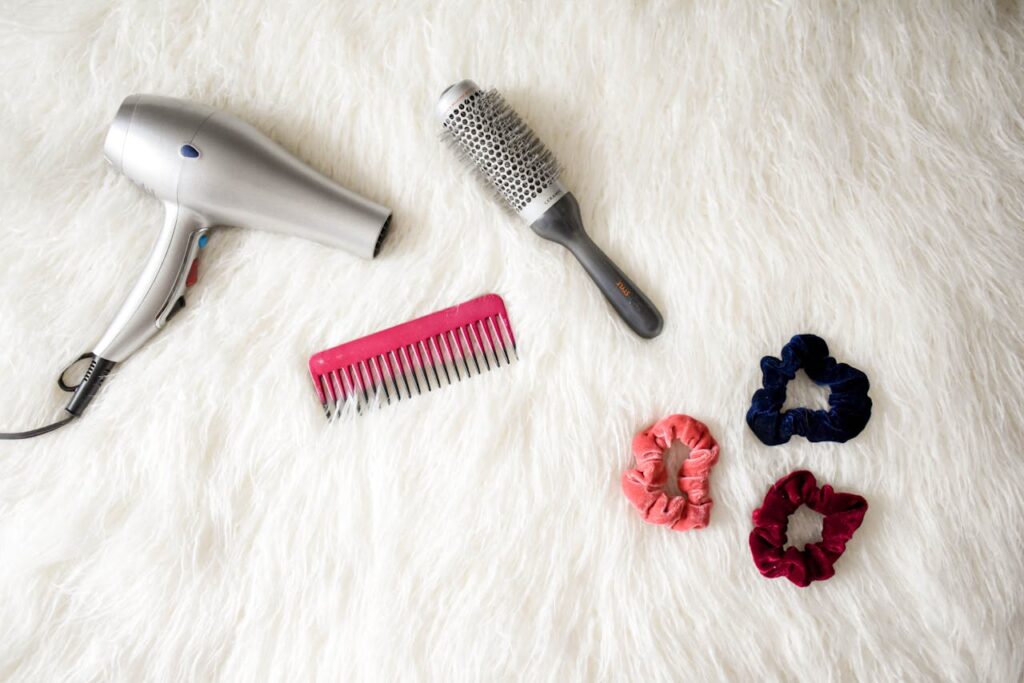 The Art of Drawing Readers In: Your attractive post title goes here Flatlay of hairstyling tools including a hairdryer, brush, comb, and scrunchies on white fur.